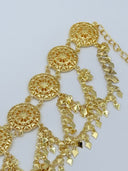 Detail of the waist belt side section showing stacked filigree coin discs, swag chains, and diamond-shaped charm drops in warm gold-tone