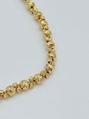 Close-up detail of the faceted diamond-cut round beads along the chain showing the graduated sizing and warm gold-tone finish