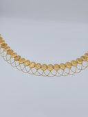 Full arc view of the gold-tone rose engraved oval medallion waist belt showing the full row of hinged medallions and multi-strand swag chains along the lower edge