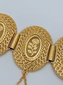 Macro close-up of a single oval medallion showing the detailed leaf-scale textured border and the engraved rose motif on the smooth oval center