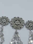 Macro close-up of three filigree rosette medallions showing the open-lattice cutwork, clear stone centers, and multi-strand coin disc drop chains