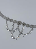 Front view of the cascading V-arrangement of coin disc drops suspended from the filigree rosette medallion row along the belt front