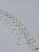 Angled view of the waist belt showing the row of octagonal panels with diamond-cut texture, polished bar hinge connectors, and cascading swag cable chains