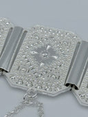 Macro close-up of a single octagonal panel showing the dense diamond-cut faceted texture, raised eight-pointed star center motif, beaded border edge, and swag cable chain attachment