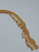 Full arc view of the gold-tone filigree panel waist belt showing the full row of hinged rectangular panels and mixed ball and diamond charm drops along the lower edge