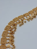 Side angle close-up of the waist belt showing the depth of the hinged filigree panels, rope-twist borders, and the mixed polished ball and diamond charm drop fringe in warm gold-tone
