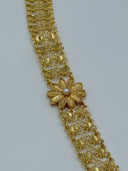 Macro close-up of a single engraved daisy flower medallion with white bead center set into the wide clover-link open mesh chain body