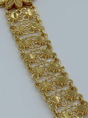 Extreme macro close-up of the wide clover-link open mesh chain body showing the interlocking loop and bead-edge texture in warm gold-tone