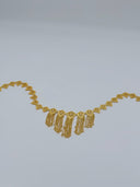 Full arc view of the gold-tone filigree heart medallion waist belt showing the full row of hinged medallions and cascading V-drape chain tassels at the front