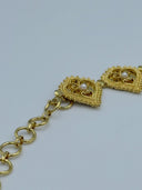 Close-up of the round-link extension chain closure end showing two filigree heart medallions with white bead centers and the round-link chain in warm gold-tone