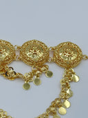 Detail view of two filigree medallions showing the jump ring connections, open-lattice body, raised floral center, and cascading coin disc swag chains below
