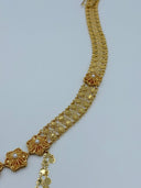 Side angle view of the waist belt showing the wide diamond-link mesh chain body, row of sunburst flower medallions, and the beginning of the V-drape coin disc drop fringe