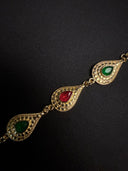 Gold bracelet with red and green gemstones on a black background