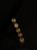 Gold floral earring on a black background