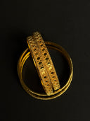 Gold bangles with intricate design on a black background