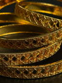 Close-up of intricately designed gold bangles on a dark background