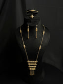 Gold-tone 4-piece jewelry set on black bust — stacked cylindrical bar pendant necklace with chain tassel fringe, drop earrings, bracelet, and ring