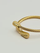 Top-down view of gold-tone twisted rope open-cuff bangle on white background