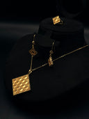 Gold-tone Cannage three-piece jewelry set on a dark display bust, showing the square lattice pendant necklace, hook-drop earrings, and matching ring