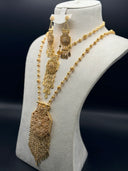 Gold-tone Rawdha layered jewelry set on a cream bust, showing two filigree sphere bead necklaces with a large hexagonal arabesque pendant and matching chandelier earrings