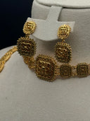 Close-up of the drop earrings and choker chain showing ornate square-link filigree motifs with beaded edges in gold tone