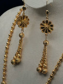 Close-up of the drop earrings showing an open-petal flower top with a dangling cluster of textured faceted beads in gold tone