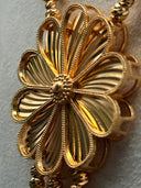 Macro close-up of the large open-petal flower pendant showing intricate filigree construction, beaded petal edges, and a center stud in gold tone
