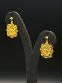 Pair of gold-tone octagonal filigree drop earrings with scrollwork borders and sunburst openwork pattern, displayed on a black velvet earring stand