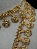 Detail shot of the opera-length necklace showing circular coin medallion pendants with sunburst motif and multi-strand box chain in gold tone