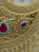Close-up of the necklace chain showing engraved rectangular bar links, round arabesque filigree coin charms, and a Khamsa-shaped filigree charm in gold tone