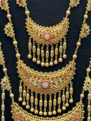 Gold-tone Rajwadi bridal set displayed on a dark bust showing a structured bracelet with a central filigree panel, a floral cocktail ring, and a pair of chandelier earrings with crescent drop bodies and tassel fringe