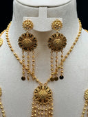 Close-up of the matching drop earrings showing a round open filigree medallion top with scrollwork detailing and a multi-strand textured bead tassel with flat coin disc ends