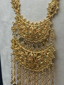 Close-up of the large opera-length crescent pendant showing the layered open filigree body with two stacked crescent tiers, raised teardrop motifs, and cascading textured chain tassel fringe with coin disc ends