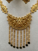 Macro close-up of the shorter crescent pendant face showing the open filigree scrollwork, raised teardrop center motif, and the row of textured chain drops with flat coin disc ends