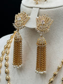 Close-up of the matching chandelier earrings showing the open lotus petal tops with pave stone setting, central oval stone, jhumka bell cap, and long chain tassel drops with white bead finishes