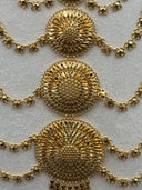 Macro close-up of three sunburst medallion stations showing the open filigree petal rays, crosshatch-engraved center dome, and the clover-link chain rows connecting them with small tassel drops