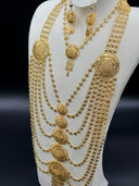 Three-quarter view of the set on a white bust showing the graduated sunburst medallions, the dense multi-strand clover-link chains, and the matching earrings with teardrop charm drops
