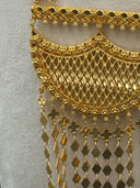Macro close-up of the large crescent pendant showing the open lattice mesh body with a scalloped granulated top bar and the dense multi-strand tassel fringe of alternating clover charms and flat diamond-shaped drops