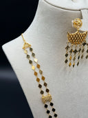 Detail shot of the upper necklace section showing the two parallel diamond-link chains, an engraved rectangular filigree connector station, and the matching earring with crescent mesh body and tassel fringe, against a dark background