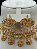 Full view of the Khaleeji-style set on a white bust against a dark background, showing two long coin disc chain necklaces, the large oval filigree pendant with clover chain fringe, and the matching chandelier earrings