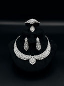 Full view of the 4-piece silver-tone zirconia set on a black bust display, showing the collar necklace, chandelier earrings, bangle, and ring