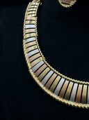 Close-up of the tri-tone ribbed collar necklace showing yellow, rose, and white bar detailing with twisted rope border edges