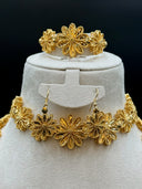 Front view of the bangle bracelet and drop earrings isolated on a white velvet stand showing three graduated flower links and hook earring construction
