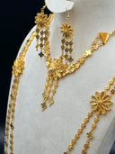 Detail of the triangle pendant cord necklace clasp and double-strand clover link chain alongside the filigree daisy drop earring on a white velvet bust