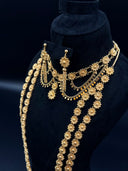 Close-up of the collar necklace and drop earrings on a black velvet bust showing filigree daisy stations, coiled bar drops, curb chain, and coin disc fringe