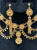 Close-up of the collar necklace and earring detail showing the filigree daisy connector, coiled bar drop, and coin disc fringe with engraved petal texture on the daisy motif