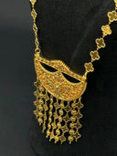 Close-up of the half-moon filigree pendant with scrolling floral cutwork and multi-strand clover and coin tassel fringe