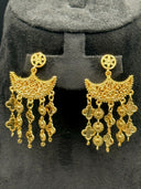 Pair of chandelier earrings displayed on a stand, showing the starburst stud, crescent filigree top, and full clover and coin tassel drops