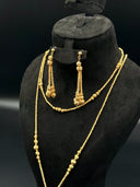 Front view of the set on a black bust highlighting the layered lariat necklace and matching long drop earrings with stacked ball texture